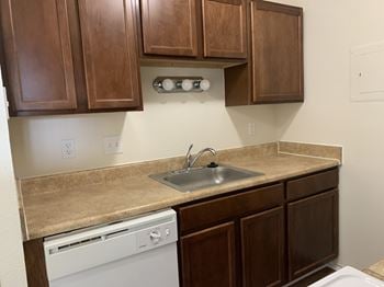 A kitchen with brown cabinets and a white dishwasher